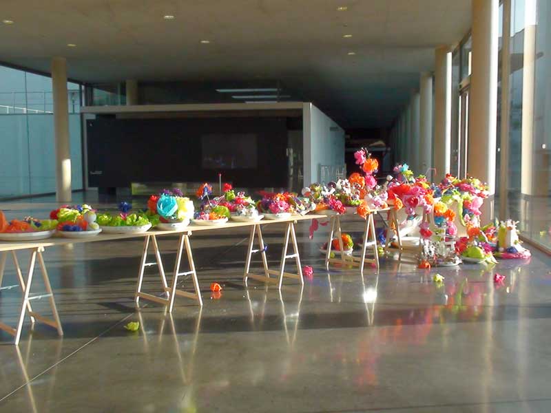 une table de 10 mtres de long, pote par des trteaux, en travers du hall d'accueil du MAC/VAL, muse d'art contemporain du Val-de-Marne. Dessus sont poss des plats ronds ou ovales en polystyrne expans qui dbordent de fleurs en papier de couleurs vives.