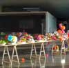 une longue table pose sur des trteaux, couverte de fleurs en papier multicolores. Lien vers une vue complte de l'oeuvre.